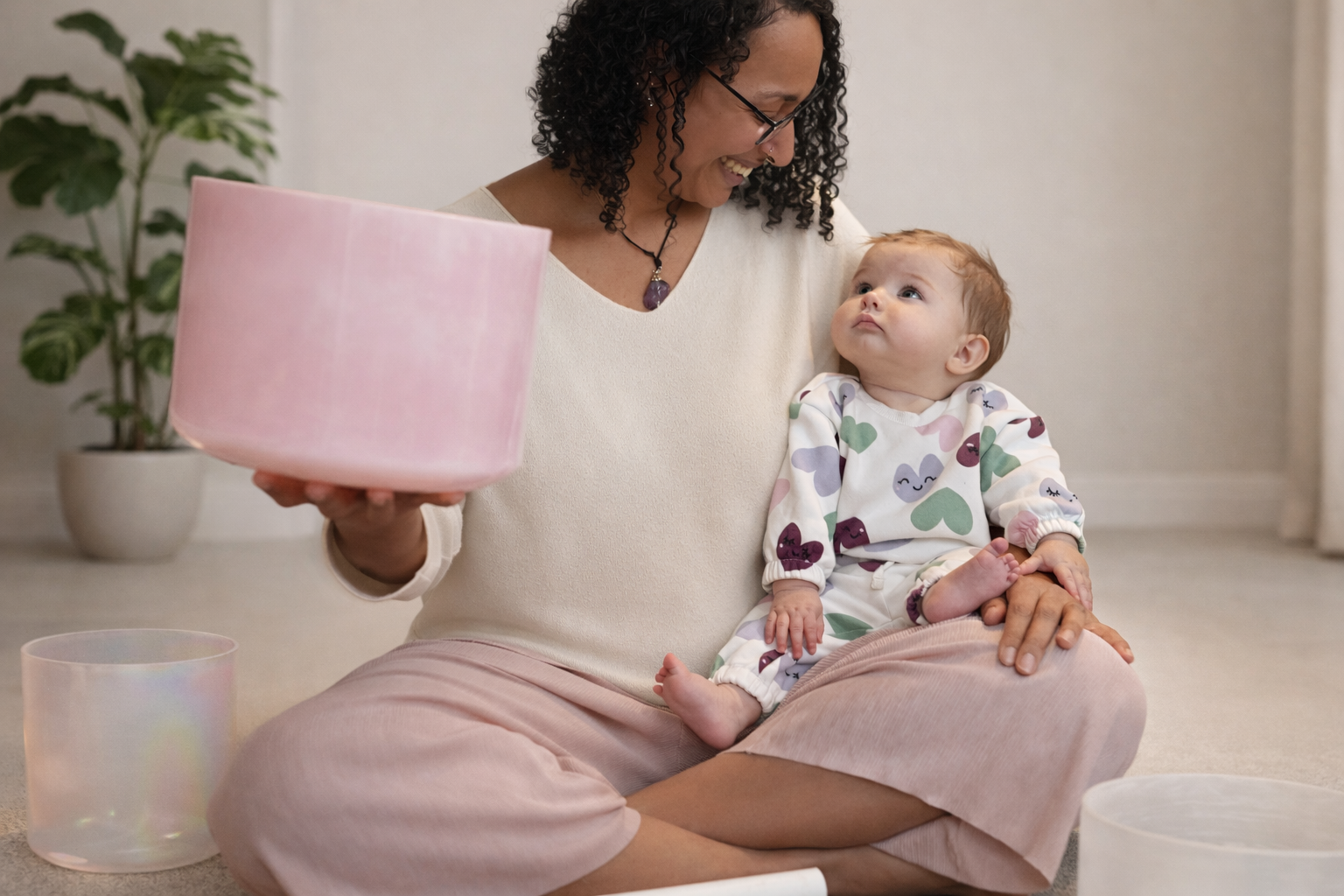 Harper in love heart tracksuit sitting on casey's lap. pink crystal singing bowl in hand