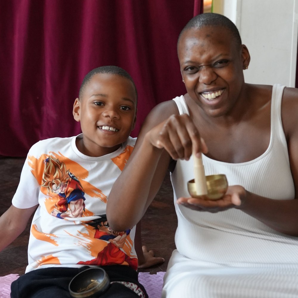 Mother and Son smiling at the camera whilst the mother plays a tibetan bowl
