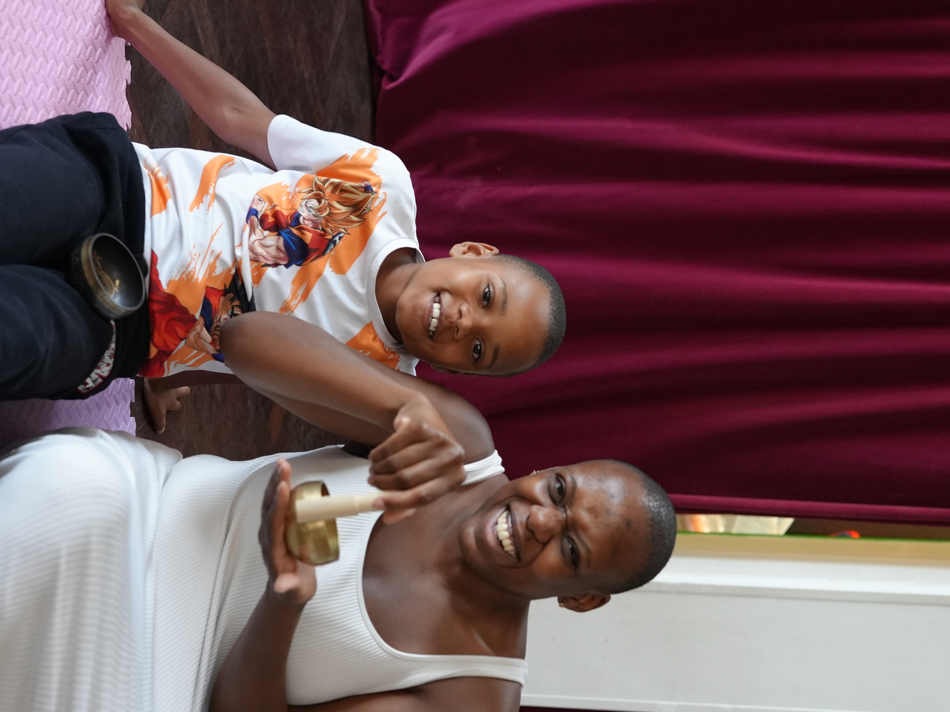Mother and Son smiling at the camera whilst the mother plays a tibetan bowl